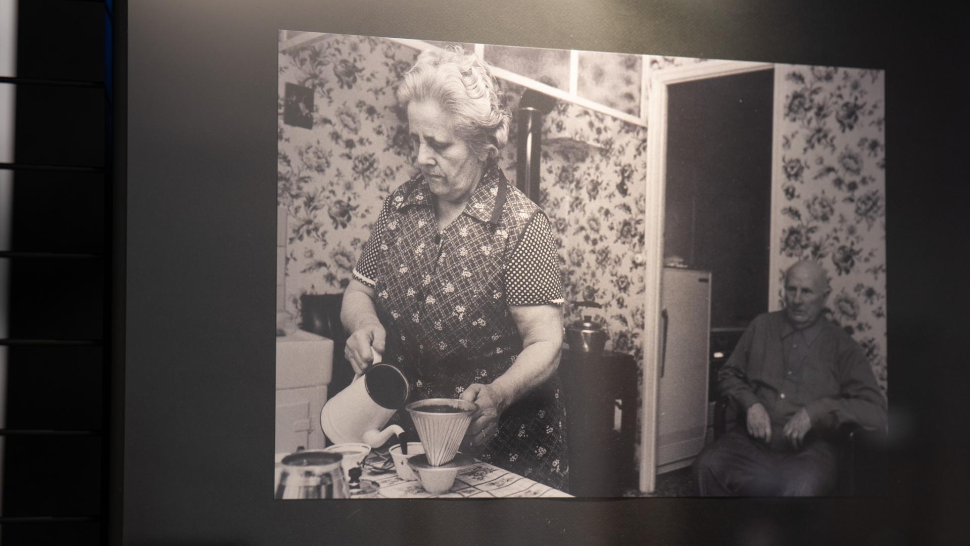Photographie de Pierre Devin d'une femme servant un café à un homme, assis derrière elle.